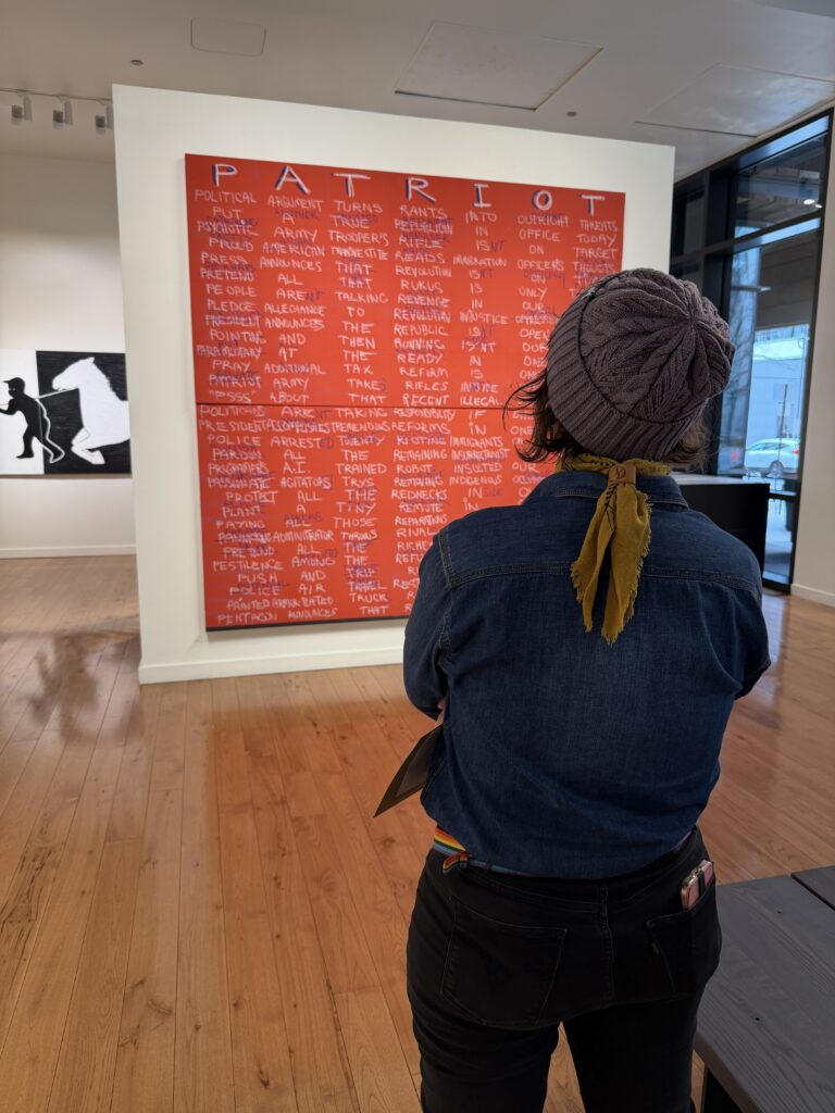 photograph of a woman viewing the a large wallhanging by artist willie cole