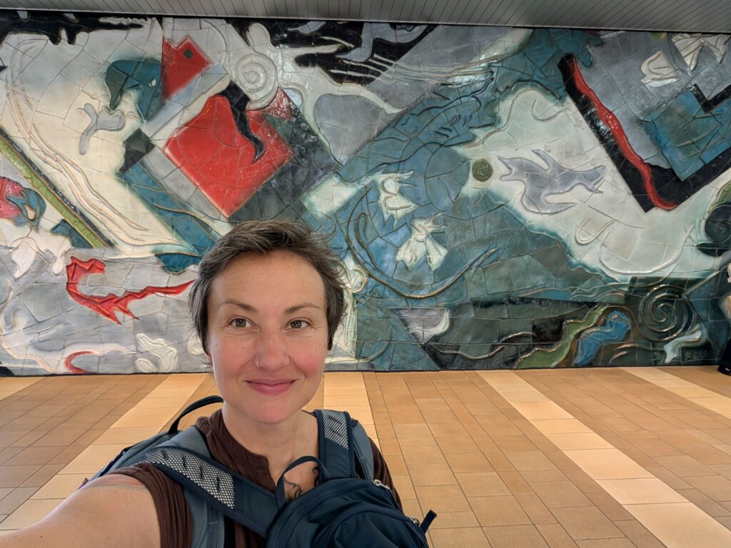 woman in front of abstract blue white and red ceramic tile mural