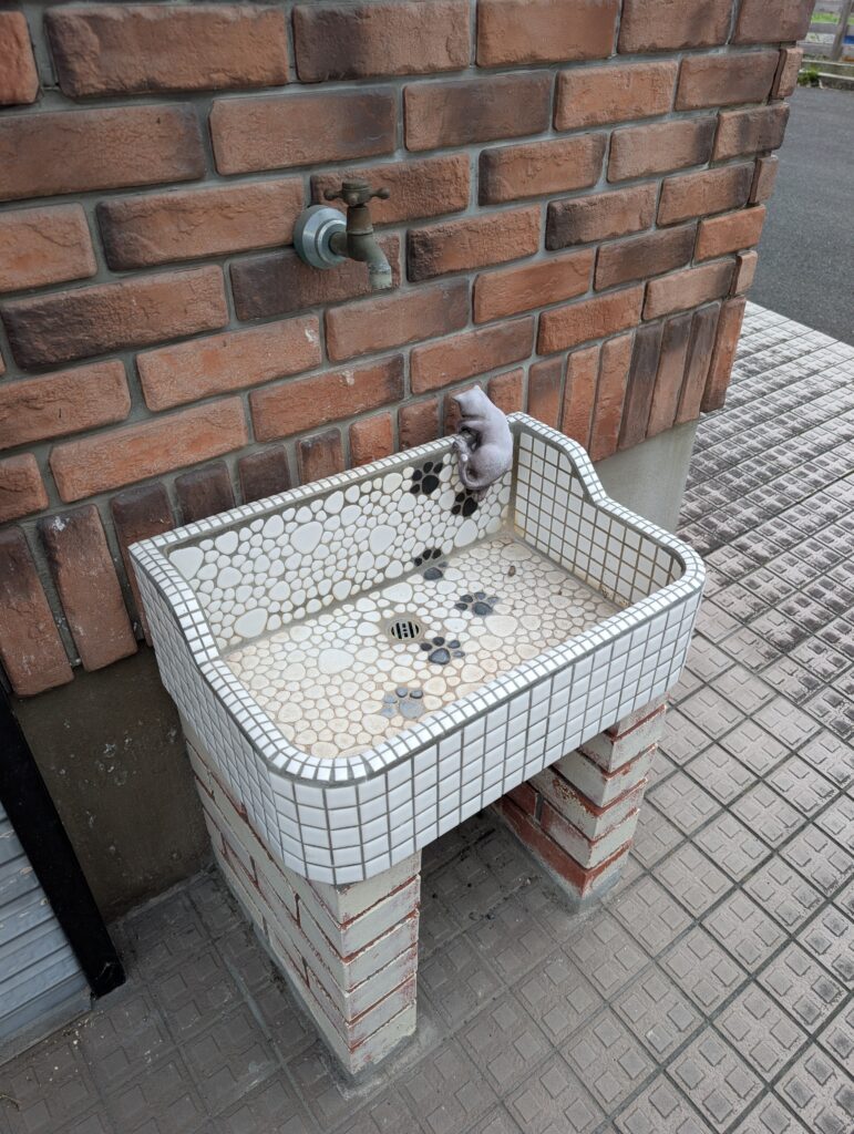 mosaic tile outdoor sink with cat prints and a ceramic cat 